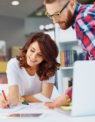 Mand and woman in an office working over a desk